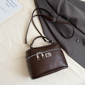 Detail of a dark brown leather vanity bag with silver twist lock and metal zipper