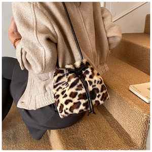 Close-up of leopard print plush bucket bag with black leather bow and drawstring detail