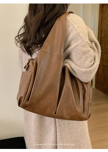 Détail d'un grand sac cabas rétro marron porté par un mannequin en tenue de maille chic