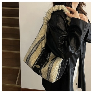 Detail of striped plush tote bag with ruffled strap and handmade metal emblem