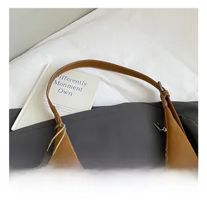 Detail of brown matte leather shoulder bag showing contrast stitching and silver buckle