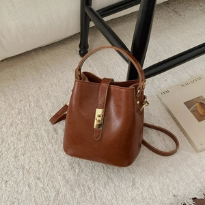 Détail d'un sac seau rétro marron avec fermoir en métal doré et finition en cuir brillant