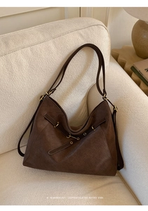 Detail of dark brown woven tote bag with gold metal buckles and adjustable leather straps