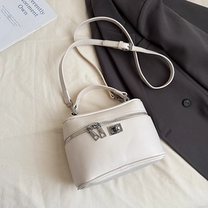 Detail of a white vanity case handbag with dual zippers and a silver twist lock buckle