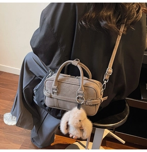 Détail du sac Boston gris avec boucles argentées et un joli porte-clés lapin rose