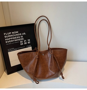 Detail view of dark brown PU leather tote bag with drawstring knots and magnetic buckle