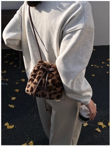 Detail of plush leopard print bucket bag with drawstring closure and bow decoration