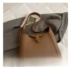 Gros plan sur le cuir grainé marron et la boucle en métal doré d'un sac à main rétro