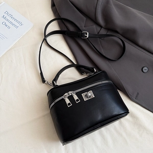 Detail view of a black box handbag featuring a dual zipper and adjustable strap