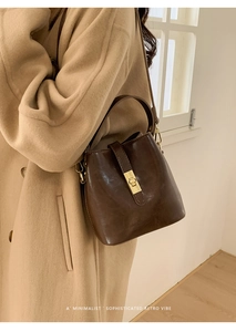 Détail du sac seau marron foncé avec fermoir doré et texture en cuir rétro minimaliste