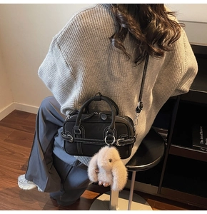 Détail du sac Boston noir avec surpiqûres blanches et pendentif lapin mignon