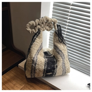 Close-up of fuzzy striped tote bag with plush twisted handle and handmade metal plaque