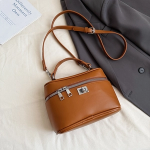 Flat lay of brown leather box handbag with dual zippers and silver twist lock detail
