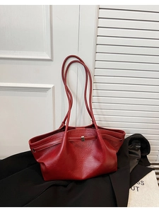 Détail du sac cabas rouge vintage sur manteau noir avec texture cuir et boucle en métal