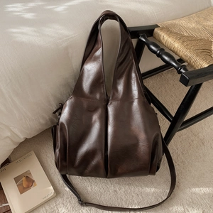 Détail du sac cabas vintage marron avec large bandoulière sur une chaise chic