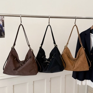 Three oversized woven hobo bags in brown, black, and tan displayed on a metal rack