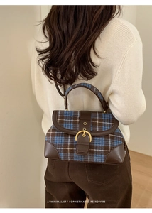 Detail of blue and brown checkered tote with leather trim and large gold buckle