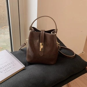 Détails du sac seau marron foncé avec fermoir rotatif doré et texture en cuir PU poli