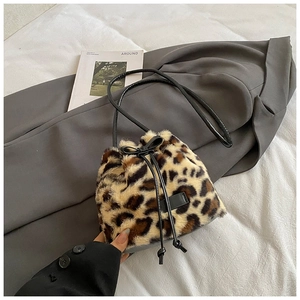 Detailed close-up of faux fur leopard bucket bag with drawstring and leather strap