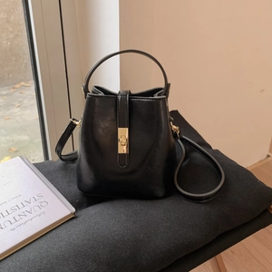 Détail d'un sac seau vintage noir avec fermoir tournant en métal doré et texture cuir lisse