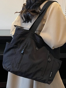Minimalist black high-capacity nylon tote bag for women shown on a model's shoulder