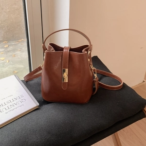 Vue détaillée du sac seau marron avec fermoir tournant doré et texture en similicuir