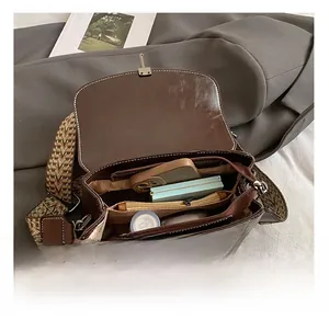 Detail view of spacious inner compartments of a vintage dark brown leather crossbody bag