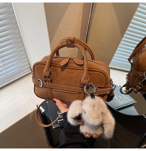 Détail du sac Boston en daim marron avec double fermeture éclair et charm lapin gris