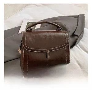 Detail showing dark brown vintage crossbody bag with silver buckle and wide geometric strap
