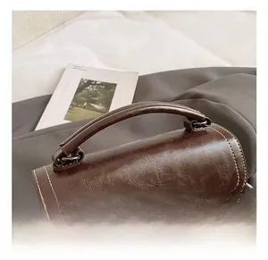 Detailed close-up of retro brown oil-wax leather bag with white contrast stitching