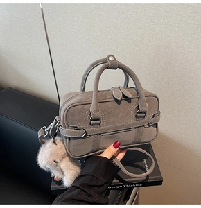 Détail du sac Boston gris en cuir dépoli avec un charmant lapin en peluche et des poignées