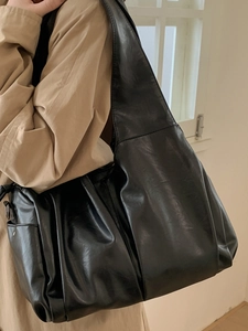 Grand sac cabas noir minimaliste en similicuir brillant porté par un mannequin