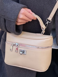 Minimalist beige box bag with silver hardware held by model in stylish winter coat
