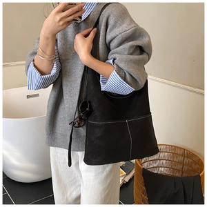 Close-up of black matte tote bag with contrast stitching and large front pocket detail