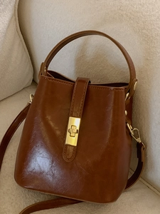 Sac seau vintage marron caramel avec fermoir doré et poignée sur canapé beige