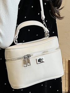 Minimalist cream box handbag with silver twist lock and dual zippers shown on model