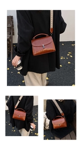 Detail of vintage brown leather bag featuring woven shoulder strap and metal buckle closure