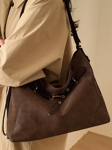 Vintage dark brown woven leather tote bag shown on model in beige trench coat