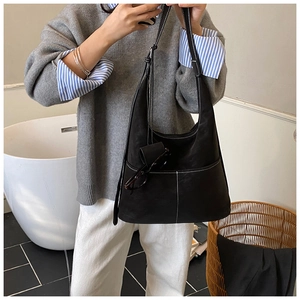 Detailed view of black leather hobo tote with contrast stitching and front pocket on shoulder