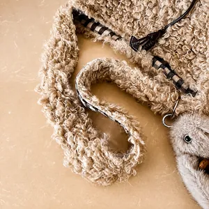 Detail of plush beige faux fur shoulder strap with gingham lining and plush doll charm