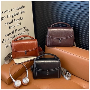 Three retro faux leather bags on leather seat with geometric patterned shoulder strap
