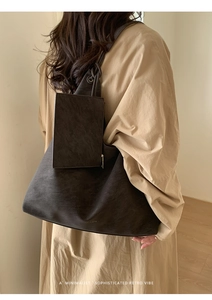 Brown leather tote bag detail with matching small pouch shown on model in minimalist setting
