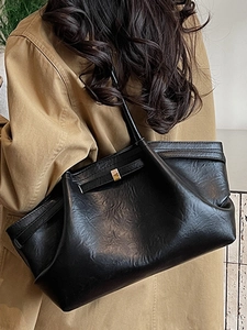 Grand sac cabas noir plissé avec boucle dorée porté sur l'épaule avec un manteau d'hiver