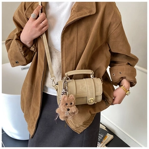 Detailansicht der beigen Retro-Zylinder-Boston-Tasche mit braunem Plüsch-Hundeanhänger