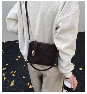 Detailed close-up of dark brown vintage crossbody bag with gold lock and metal rivets