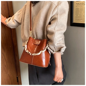 Close-up of brown leather bucket bag with silk scarf metal chain and adjustable strap