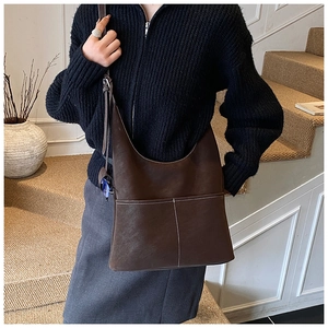 Close-up of brown suede hobo bag featuring white contrast stitching and front pockets