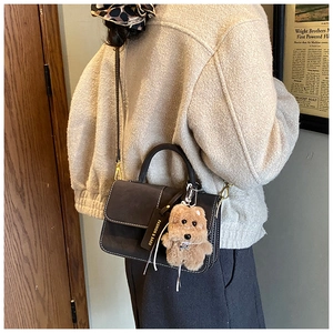 Detail of dark grey matte shoulder bag with cute teddy bear charm and fashion tag