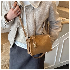 Detail of vintage caramel brown crossbody bag with metallic turn-lock and leather texture