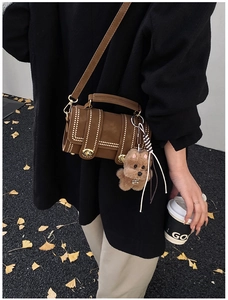 Detailansicht der Retro-Boston-Tasche in Braun mit Nieten und süßem Plüsch-Anhänger